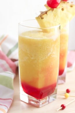 A glass of Bahama Mama drink garnished with pineapple and cherries