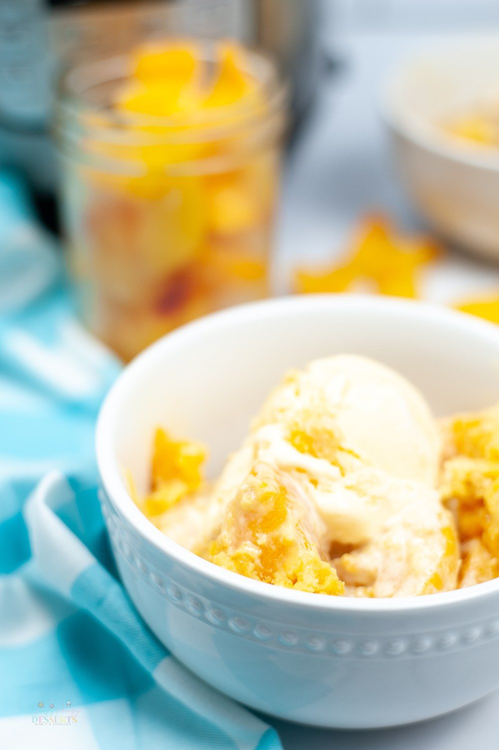 Side image of instant pot peach cobbler in a white bowl, topped with vanilla ice cream