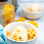 Side image of peach cobbler in a white bowl, topped with vanilla ice cream