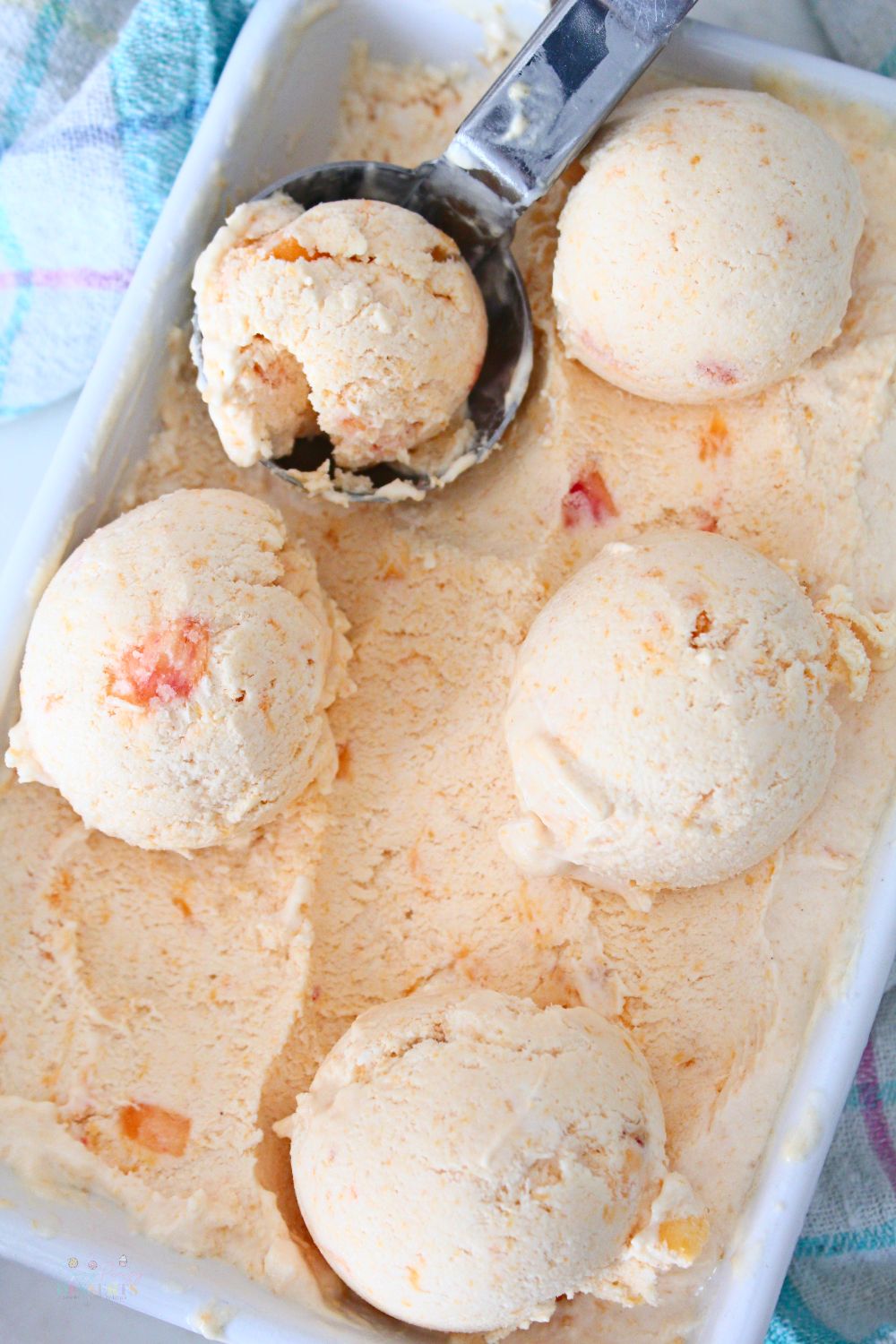 A few balls of peach ice cream in an ice cream container