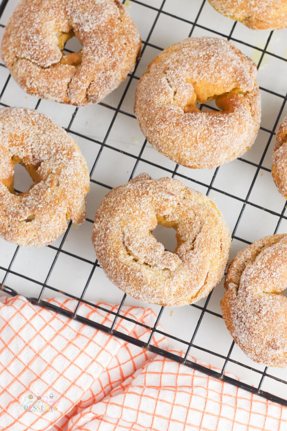 Air fryer donuts on a cooling rack next to a checkered napkin