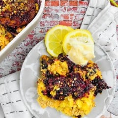Blackberry dump cake on a white serving plate, next to a baking dish filled with the same cobbler