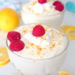 Easy lemon mousse in ice cream cups, garnished with raspberries, lemon zest and a dollop of whipped cream