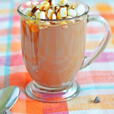 Spiked hot chocolate in a mug, decorated with marshmallows and chocolate syrup and caramel syrup