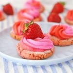 Image of strawberry cream cookies decorated with cream cheese frosting and fresh strawberries, on a serving plate