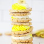 Close up image of a stack of banana cookies with white and yellow cream cheese frosting