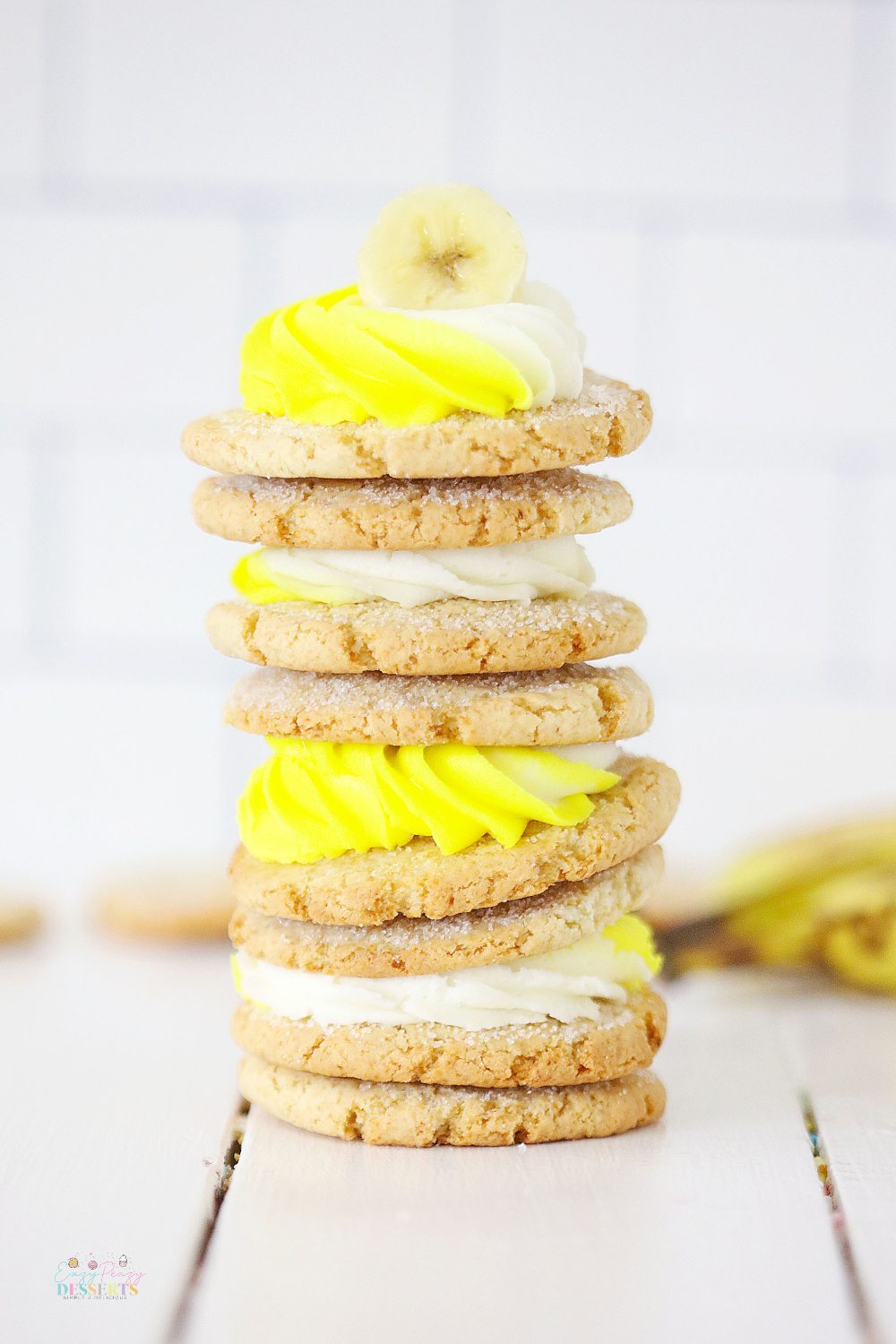 Close up image of a stack of banana cookies with white and yellow cream cheese frosting