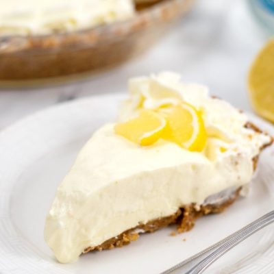 Image of a slice of lemon pie in a serving plate, decorated with a slice of lemon