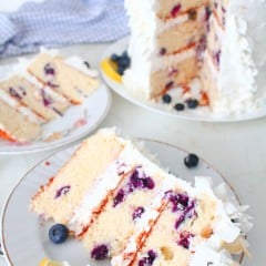 A slice of lemon and blueberry cake decorated with lemon and fresh blueberries