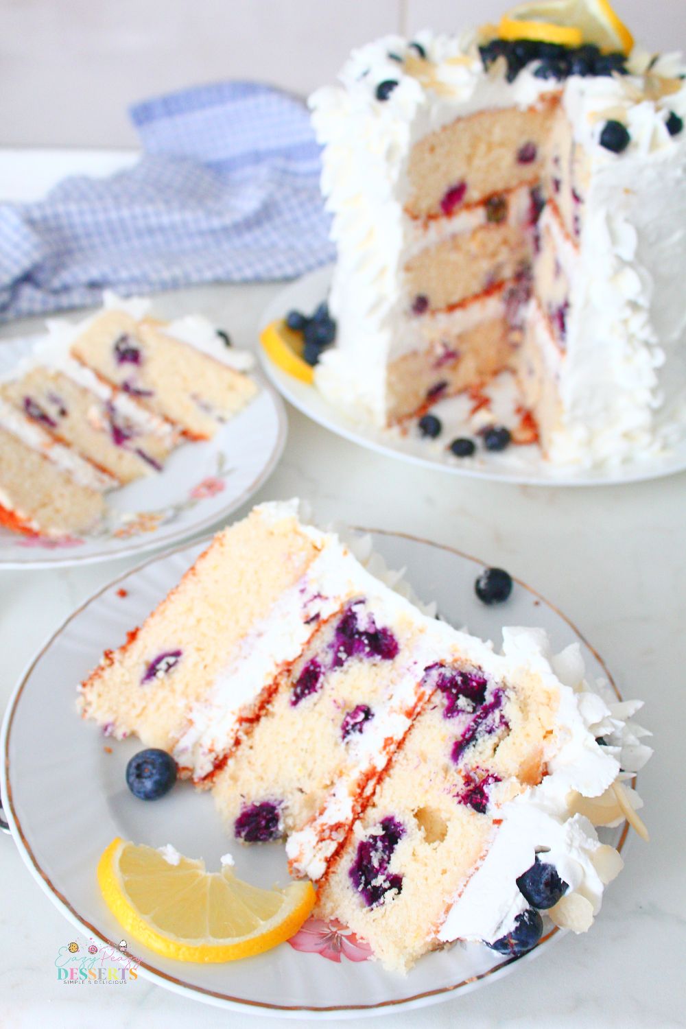 A slice of lemon and blueberry cake decorated with lemon and fresh blueberries