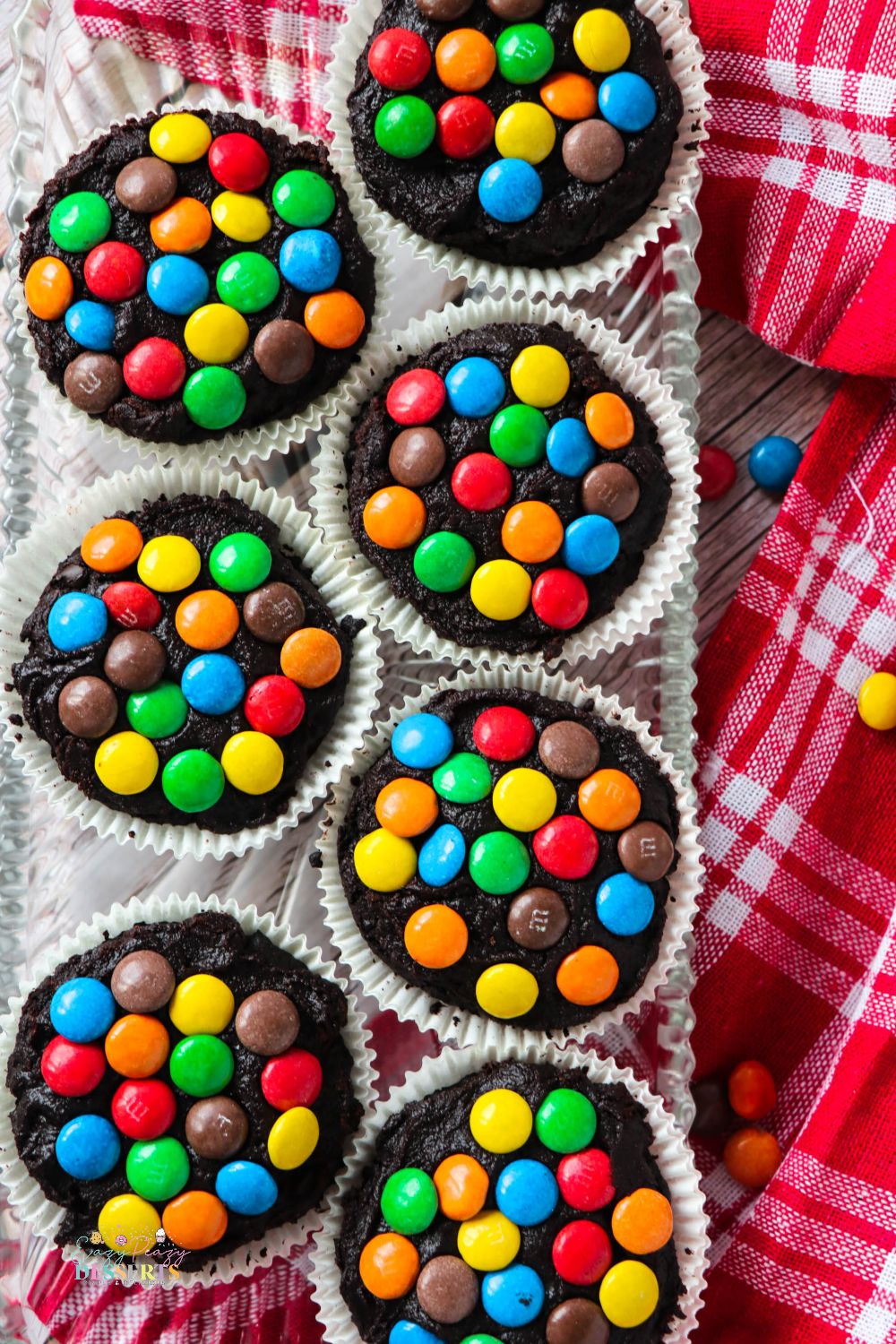 Over head image of a few chocolate frosting cupcakes decorated with M&M's