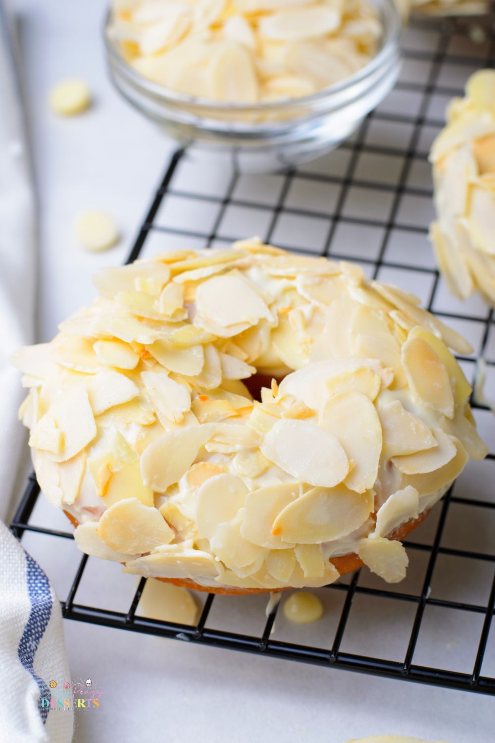 Close up image of yeast donut covered in white chocolate glaze and shaved almonds