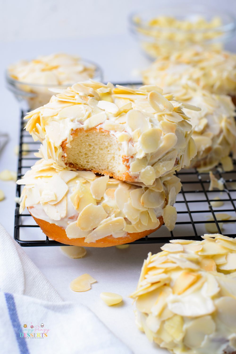 Image of two raised donuts covered in white chocolate glaze and shaved almonds