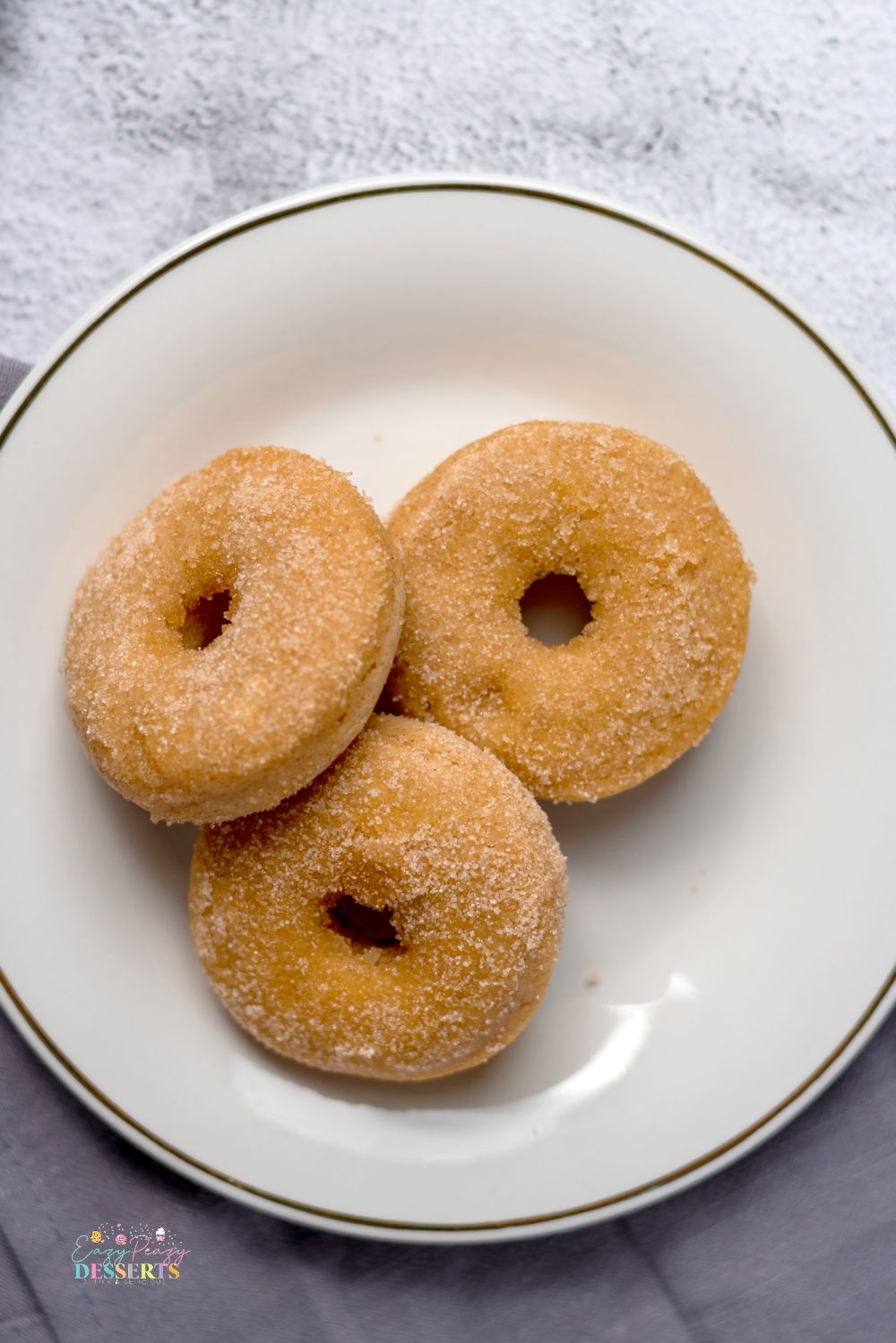 Image of three vegan cinnamon donuts on a desserts plate
