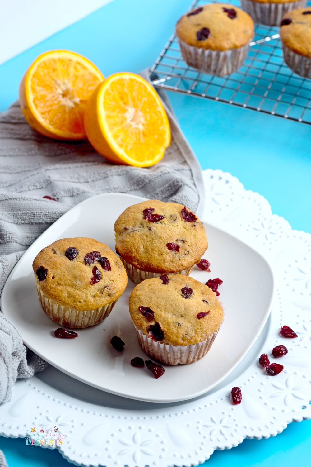 Three healthy cranberry orange muffins on a white serving plate