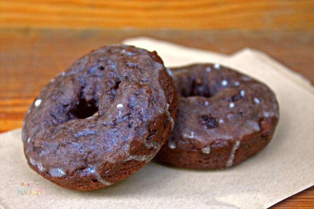 Image of a couple of glazed chocolate donuts on baking paper