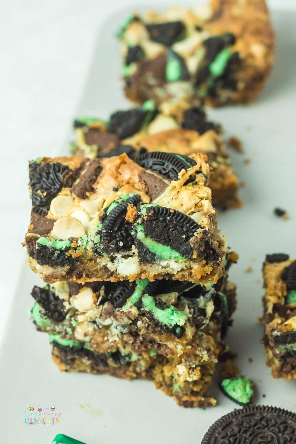 Angle image of a few mint Oreo cookie bars on a white serving plate